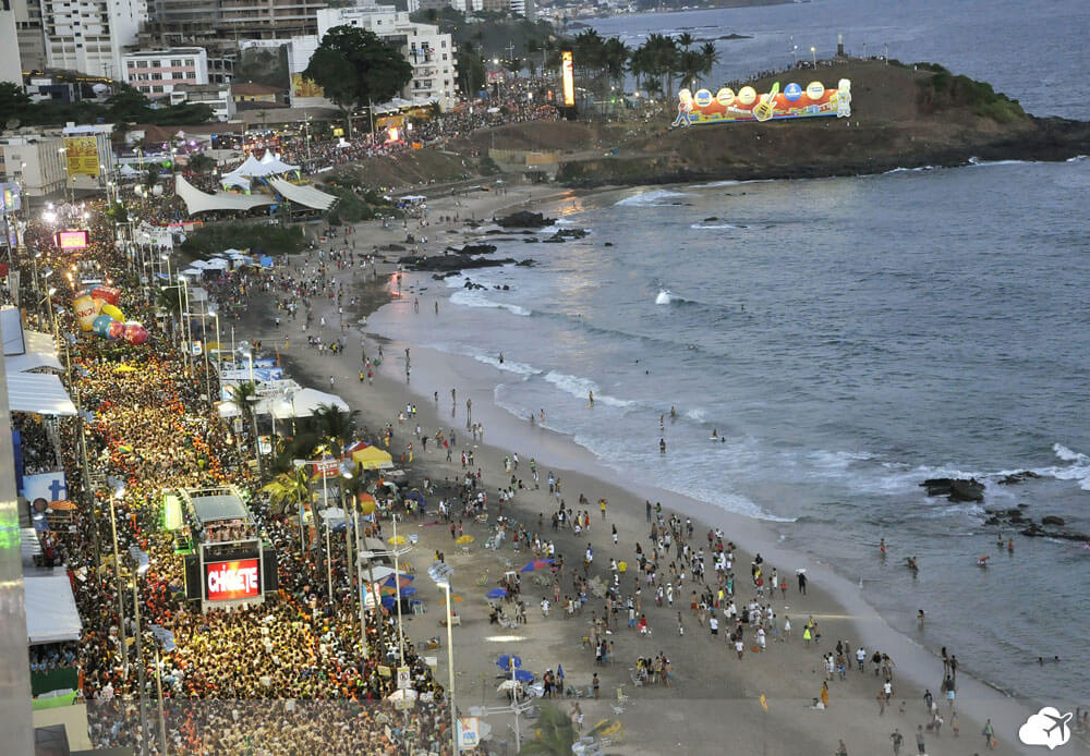 Foto da praia com foliões ao longo da orla em Salvador